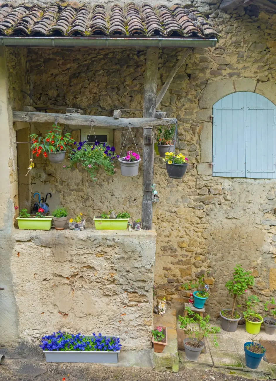 Longère en pierre rénovée, volets bleus et façade fleurie