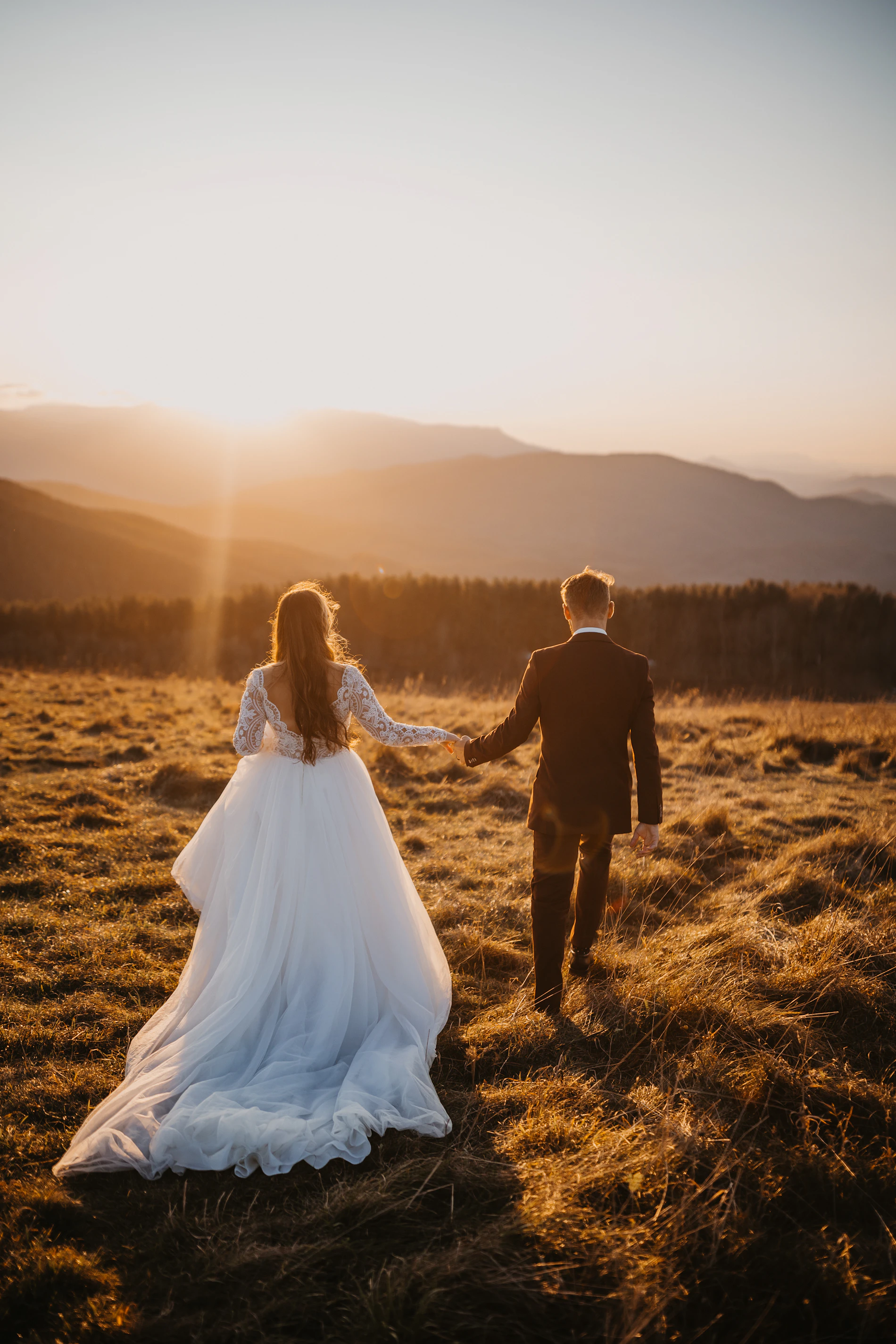 Couple de mariés au coucher du soleil dans un champ doré